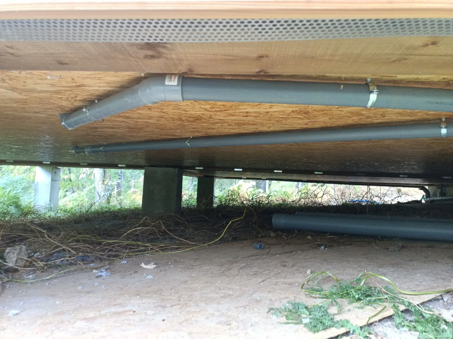 Réseau PVC fixé sous le plancher de la maison en bois
